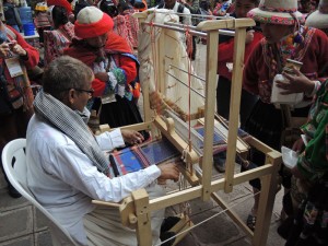 Peruvian weavers watching Dayabhai weave his traditional motifs. Note the checked shawl around his neck. 